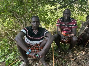 Two Pokot warriors sit under a tree in the fora